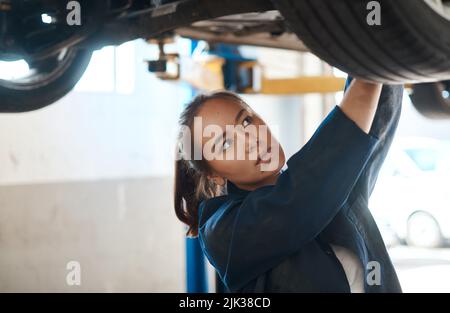 Detecting problems and doing repairs is what I do. a female mechanic working under a lifted car. Stock Photo