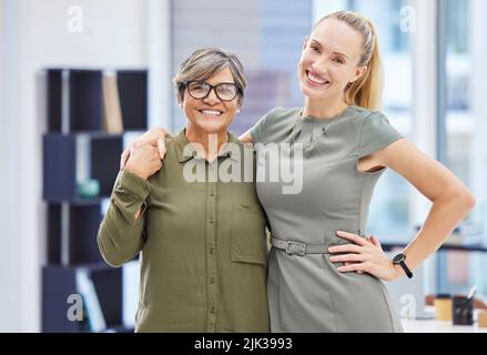 Colleagues are best friends in disguise. two businesswomen standing together in the office with their arms around each other. Stock Photo