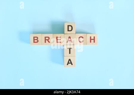 Data breach concept. Wooden block crossword puzzle flat lay in blue background. Stock Photo