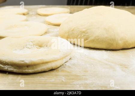 Dough rolled out on the table in the form of cakes. The dough for baking is rolled out and shaped into cakes. Background with copy space Stock Photo