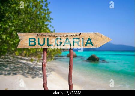 Bulgaria wooden arrow road sign against beach with white sand and turquoise water background. Travel to Bulgaria concept. Stock Photo