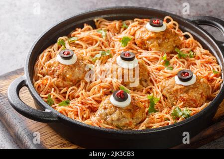 halloween Spaghetti with tomato sauce and meatballs with eyes in a frying pan on the table close-up. Horizontal Stock Photo