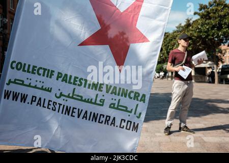 Toulouse, France. 30th July, 2022. A member of the Collective distributing leaflets, and flag of the Collective. At the call of the Collectif Palestine Vaincra, rehabilitated by the Council of State a few weeks ago, several activists organized an information stand for the boycott of the Champions Trophy (Trophée des Champions), and more broadly of Israeli products. The Champions Trophy is a football match between PSG (champion of Ligue 1) and FC Nantes (winner of the Coupe de France) on July 31, 2022 in Tel Aviv (Israel). For the Collective, this trophy is a commercial operation organized by t Stock Photo