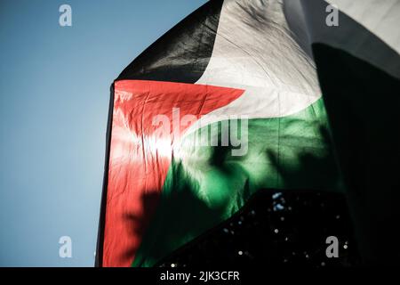 Toulouse, France. 30th July, 2022. Sun trough the Palestine flag. At the call of the Collectif Palestine Vaincra, rehabilitated by the Council of State a few weeks ago, several activists organized an information stand for the boycott of the Champions Trophy (Trophée des Champions), and more broadly of Israeli products. The Champions Trophy is a football match between PSG (champion of Ligue 1) and FC Nantes (winner of the Coupe de France) on July 31, 2022 in Tel Aviv (Israel). For the Collective, this trophy is a commercial operation organized by the Professional Football League, around promote Stock Photo