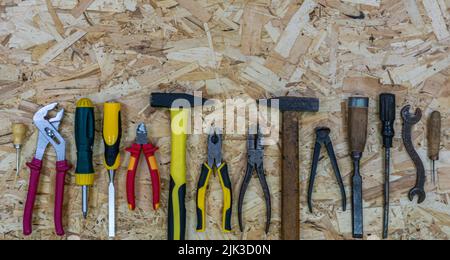 Old rusty tools near modern tools on the OSB sheet. Concept: equipment upgrade. Tools: Hammer and pliers, chisel and screwdriver, awl amd wrench. Stock Photo