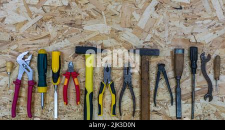 Old rusty tools near modern tools on the OSB sheet. Concept: equipment upgrade. Tools: Hammer and pliers, chisel and screwdriver, awl amd wrench. Stock Photo