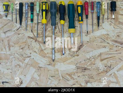 Many screwdrivers from small to large, arranged in size on the OSB plate on top. Place for text or logo. Stock Photo