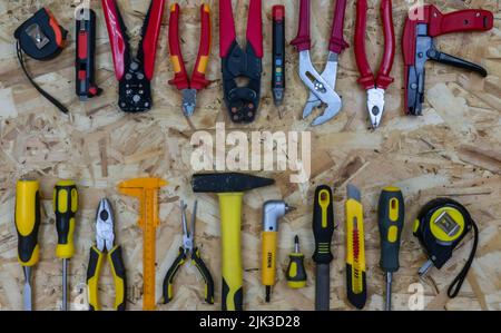 A red construction tools opposite a yellow working tools on a osb plate background. Place for text between them. Concept: the battle of tools. Stock Photo