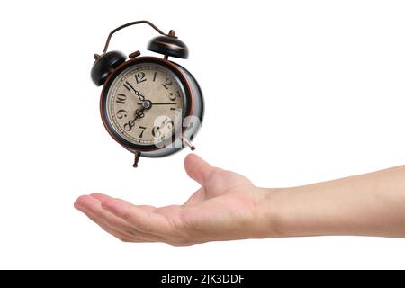 Ringing and hovering old retro alarm clock above hand on white background Stock Photo