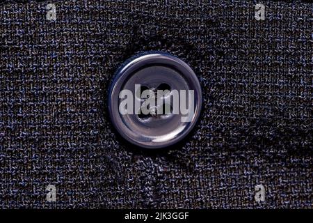 Macro photo of a sewing button on a dark blue fabric pattern isolated background. High quality photo Stock Photo