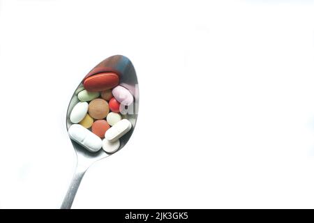 Close up of many colorful pills and capsules on a spoon isolated on white  Stock Photo
