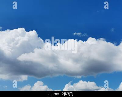 Fluffy clouds covering blue sky on a summer day Stock Photo