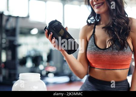 Young active woman taking a break in the gym and drinking protein shake. Stock Photo