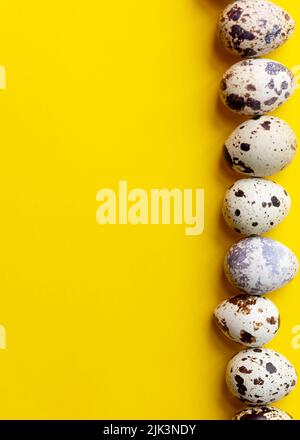 Top view - Quail eggs on bright yellow background. Minimal Happy Easter composition. Stock Photo