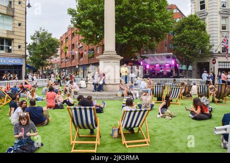 London, UK. 30th July 2022. People enjoy live music on artificial turf at Seven Dials in London's West End, which has been blocked for traffic for the one-day Summer Sessions festival. Credit: Vuk Valcic/Alamy Live News Stock Photo