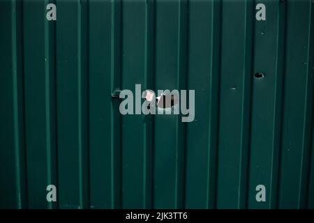 Fence near the house with bullet holes and charapnels after gunshots and fighting during the invasion of Russian troops into Ukraine Stock Photo