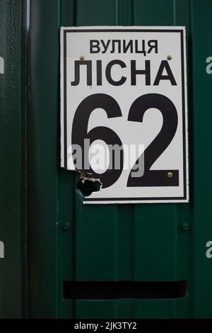 Fence near the house with bullet holes and charapnels after gunshots and fighting during the invasion of Russian troops into Ukraine Stock Photo