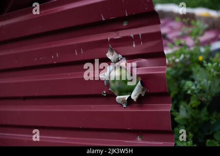 Fence near the house with bullet holes and charapnels after gunshots and fighting during the invasion of Russian troops into Ukraine Stock Photo