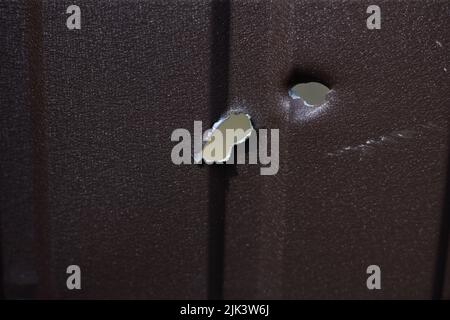 Fence near the house with bullet holes and charapnels after gunshots and fighting during the invasion of Russian troops into Ukraine Stock Photo