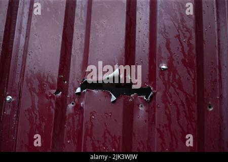 Fence near the house with bullet holes and charapnels after gunshots and fighting during the invasion of Russian troops into Ukraine Stock Photo