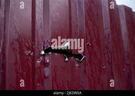 Fence near the house with bullet holes and charapnels after gunshots and fighting during the invasion of Russian troops into Ukraine Stock Photo