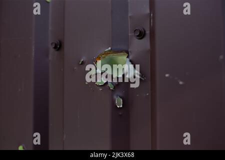 Fence near the house with bullet holes and charapnels after gunshots and fighting during the invasion of Russian troops into Ukraine Stock Photo