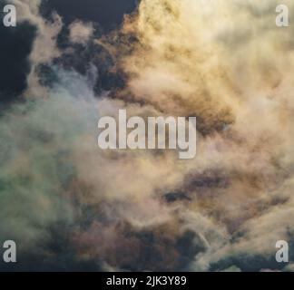 Diffraction of light on drops of supercooled water in clouds, rainbow clouds against the blue sky in clear sunny weather, irisation of cumulus clouds Stock Photo