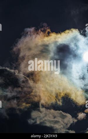 Diffraction of light on drops of supercooled water in clouds, rainbow clouds against the blue sky in clear sunny weather, irisation of cumulus clouds Stock Photo