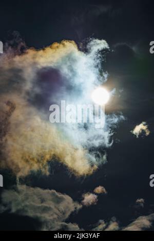 Diffraction of light on drops of supercooled water in clouds, rainbow clouds against the blue sky in clear sunny weather, irisation of cumulus clouds Stock Photo