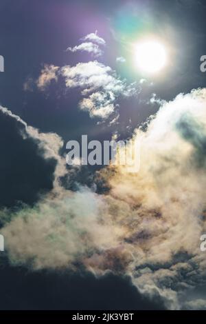 Diffraction of light on drops of supercooled water in clouds, rainbow clouds against the blue sky in clear sunny weather, irisation of cumulus clouds Stock Photo