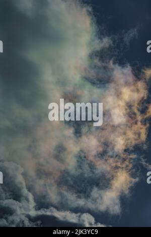 Diffraction of light on drops of supercooled water in clouds, rainbow clouds against the blue sky in clear sunny weather, irisation of cumulus clouds Stock Photo