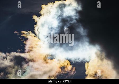 Diffraction of light on drops of supercooled water in clouds, rainbow clouds against the blue sky in clear sunny weather, irisation of cumulus clouds Stock Photo