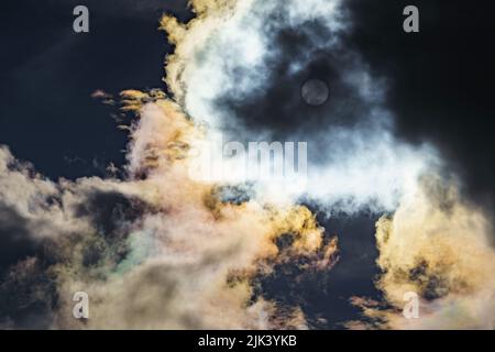 Diffraction of light on drops of supercooled water in clouds, rainbow clouds against the blue sky in clear sunny weather, irisation of cumulus clouds Stock Photo