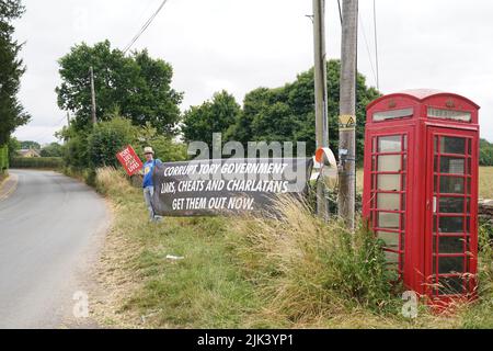 A protester near Daylesford House in Gloucestershire, where Prime Minister Boris Johnson and wife Carrie are holding a first wedding anniversary party for friends and family. Picture date: Saturday July 30, 2022. Stock Photo