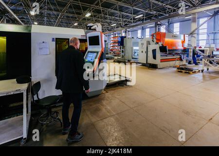 Factory worker operating CNC machine in metalworking workshop. Stock Photo