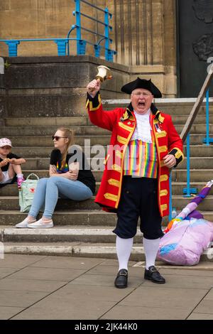 Town crier standing outside Norwich city hall shaking his bell for the start of the LGBT Pride march Stock Photo