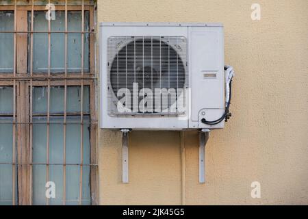 old outdoor air conditioner unit hanging outside the building Stock Photo