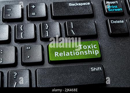 Toxic relationship words on the green enter key of a desktop computer keyboard. Concept of unsupported, misunderstood, demeaned relationship online. Stock Photo