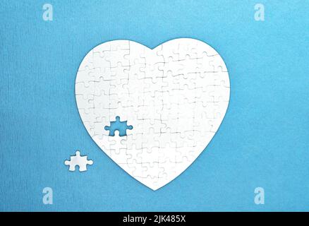 White puzzles shape of heart on blue background. Health care concept Stock Photo