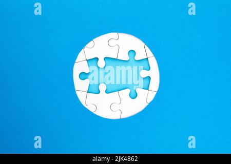 Frame of white puzzles on blue background. Place for your text. Mockup Stock Photo