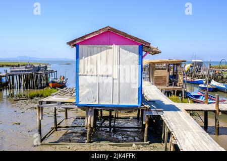 Old wood fisherman hut painted in white and blue in a rotten pier during low tide in a sunny day Stock Photo