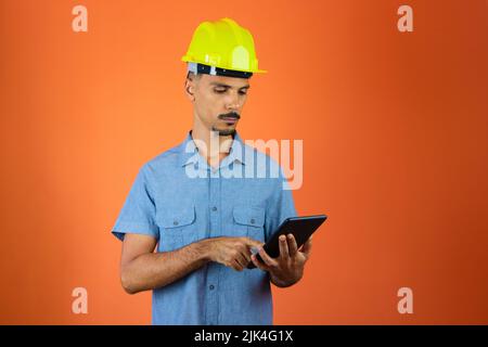 Engineer Holding Mobile isolated on Orange. Stock Photo