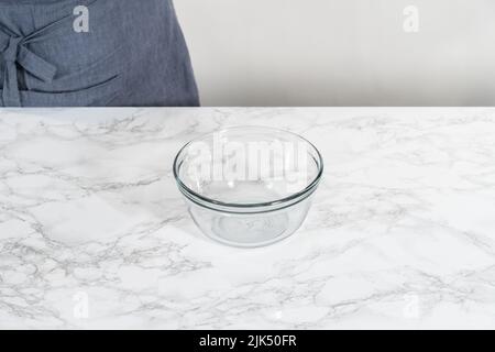 Activating dry yeast in a glass mixing bowl to bake mini Easter bread kulich. Stock Photo