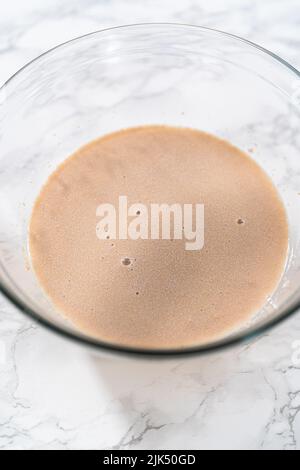 Activating dry yeast in a glass mixing bowl to bake mini Easter bread kulich. Stock Photo