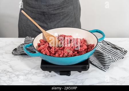 Browning ground beef in cast iron skillet to make homemade hamburger helper. Stock Photo