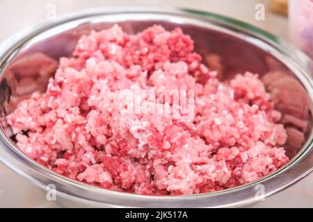 A man mixes minced meat in a bowl with his hands. Preparation of minced beef and pork for cutlets, meatballs, chops. Stock Photo