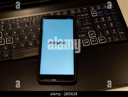 illustration of the Amazon logo displayed on a smartphone screen , background is a computer keyboard Stock Photo