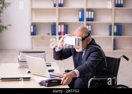 Old leg injured businessman employee wearing virtual glasses in the office Stock Photo