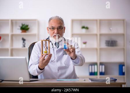 Old doctor in time management concept Stock Photo