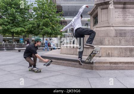 New York, NY/USA - 05-07-2016: Young filmmaker video tapes skateboarder at a park in Manhattan. Stock Photo